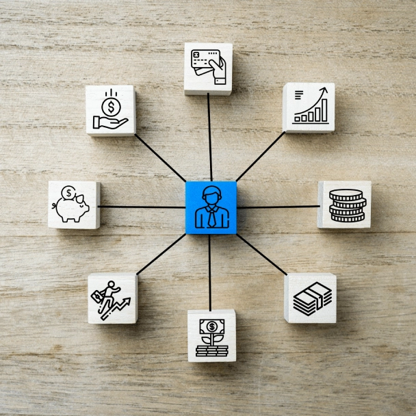 A central blue icon of a businessman is connected to various financial and investment icons on wooden blocks.